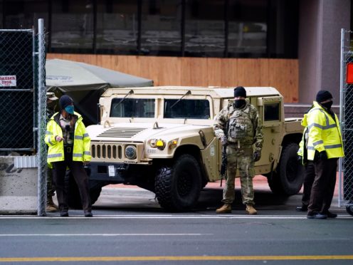 A National Guard soldier, centre, stands guard with deputies at the restricted vehicle entrance of the Hennepin County Government Centre (Jim Mone/AP)