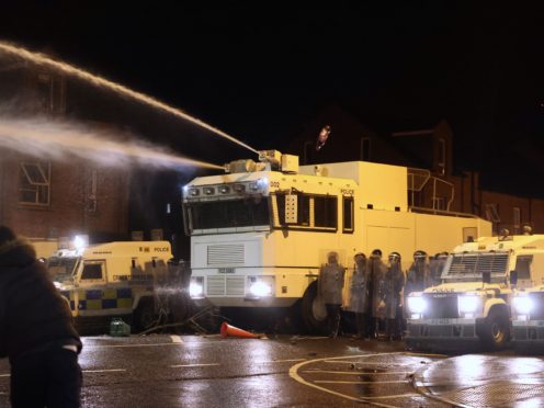 Objects are thrown towards PSNI officers an the water cannon on Springfield Road in Belfast (Liam McBurney/PA)