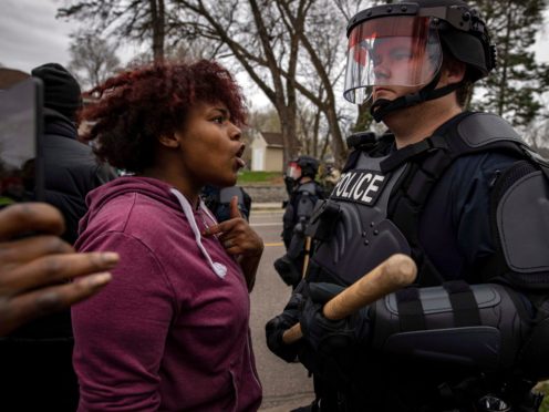 A person confronts a police officer near the site where a family said a man was shot and killed by local law enforcement in Brooklyn Centre, Minnesota (Christian Monterrosa/AP)