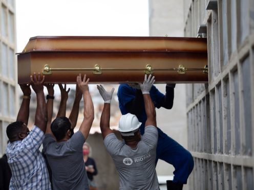 A coffin is placed into a niche by cemetery workers at the Inahuma cemetery in Rio de Janeiro, Brazil (Silvia Izquierdo/AP)