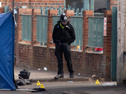 A police officer inspects the scene at an industrial premises on Western Road near Birmingham’s City Hospital where a murder investigation has been launched after a fatal shooting (Jacob King/PA)