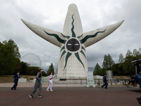 An Olympic torch relay runner, centre left, carries the torch on the second day of the Osaka leg in Suita, north of Osaka, western Japan (Hiro Komae/AP)