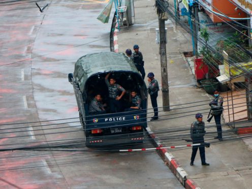 Police security forces stand by inside a police vehicle and on the sidewalk of Hledan Road in Kamayut township in Yangon, Myanmar (AP)