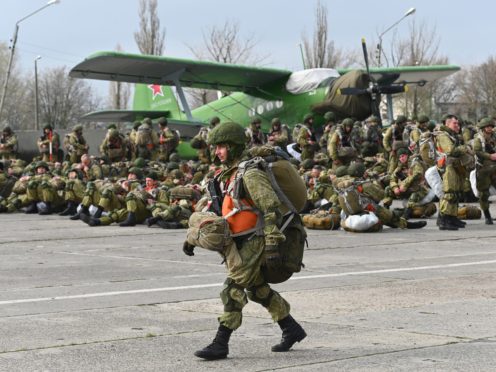 A Russian paratrooper walks as others wait to be loaded into a plane for airborne drills during manoeuvres in Taganrog, Russia (AP)