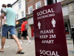 People walk past a social distancing sign on the high street in Winchester (Andrew Matthews/PA)