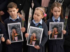 Pupils from Ashling Murphy’s class hold photographs of her (Niall Carson/PA)