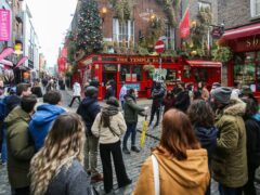 A tour group leader stops with tourists at the Temple Bar in Dublin on the day coronavirus restrictions were eased across Ireland (PA)
