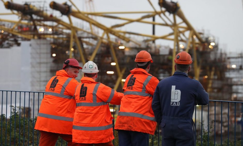 Workers at BiFab look on at turbine jackets.