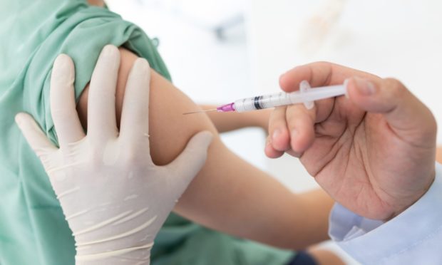 Close up of a Doctor making a Covid vaccination in the shoulder of patient.