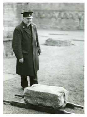 The curator of Arbroath Abbey standing by the Stone of Scone in 1951.