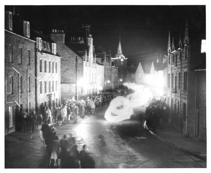 An eerie and mesmerising shot of the Stonehaven Fireballs in 1976, as circles of light are seen swirling down the street.
