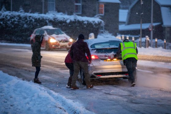 Good Samaritans helping to push cars on an icy curve off Glasgow Road, Perth.