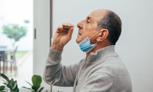 A man swabbing his nose with equipment from a lateral flow test
