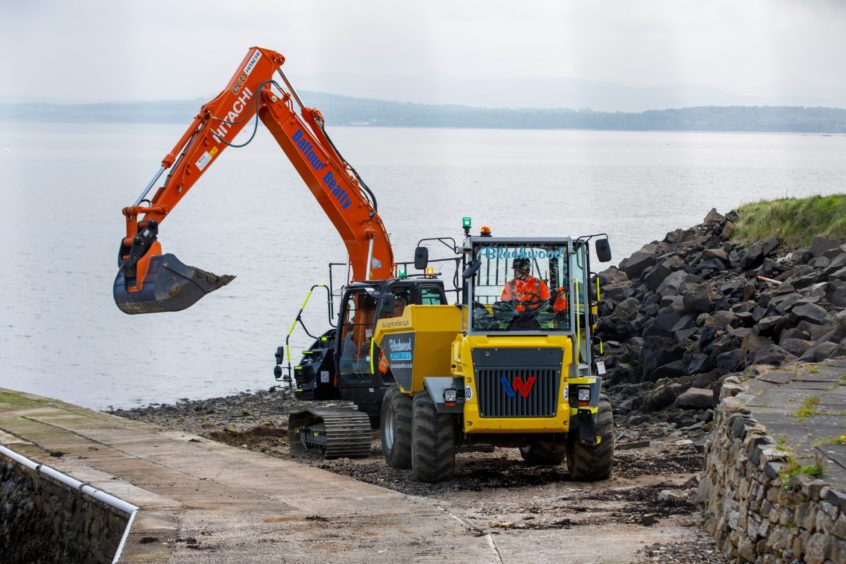 A digger clears contaminated material from the beach at Dalgety Bay.