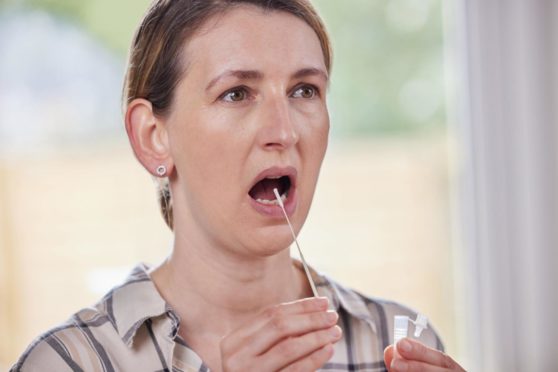 A woman swabbing her mouth taking a rapid lateral flow test