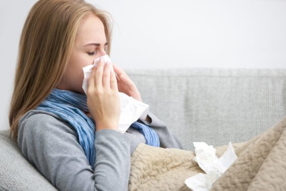 a woman blowing her nose - one of the most common hay fever symptoms