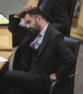 Humza Yousaf scratches his head in his chair at Holyrood.