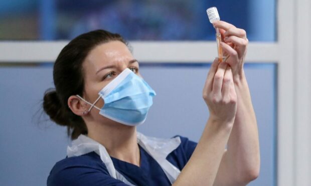 A healthcare worker fills a syringe with a dose of the Covid vaccine at a clinic
