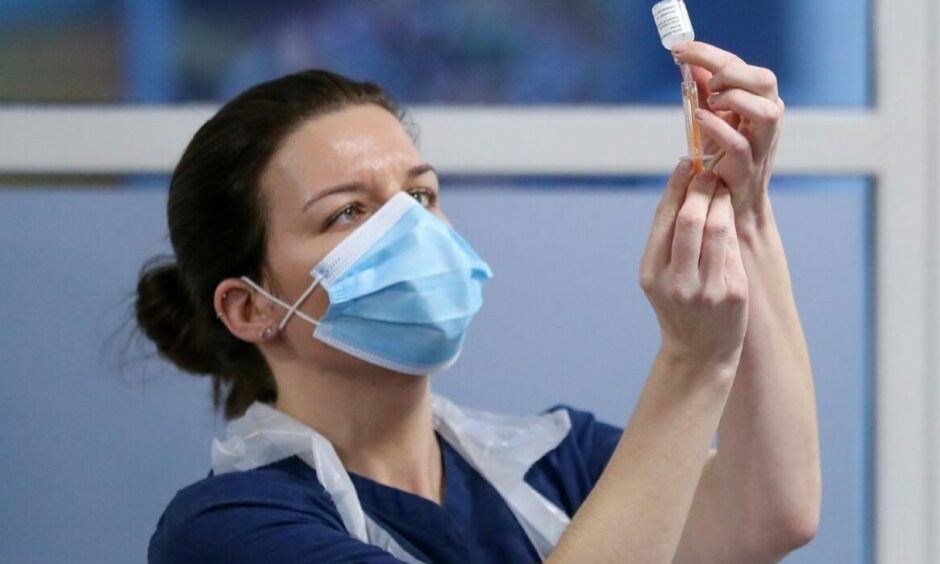 A healthcare worker fills a syringe with a dose of the Covid vaccine at a clinic