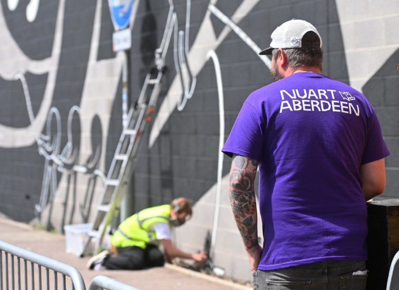 KMG works on her Palmerston Road mural. 