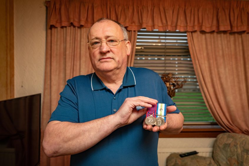 Charles Haffey holding the George Medal he was awarded for his part in the 1988 rescue efforts.