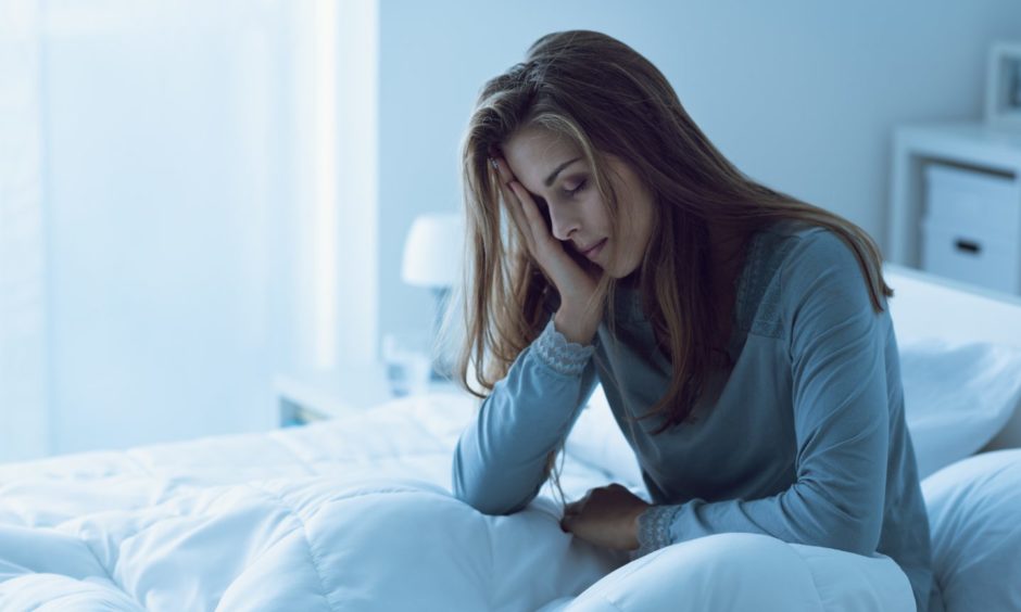 A woman sitting up in bed holding her face