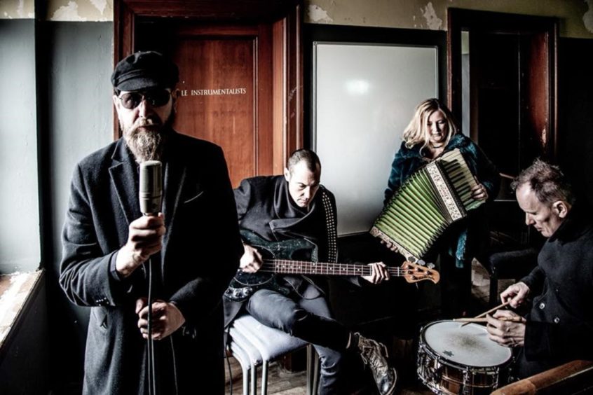 The band Goodbye Mr Mackenzie posing with instruments in a room