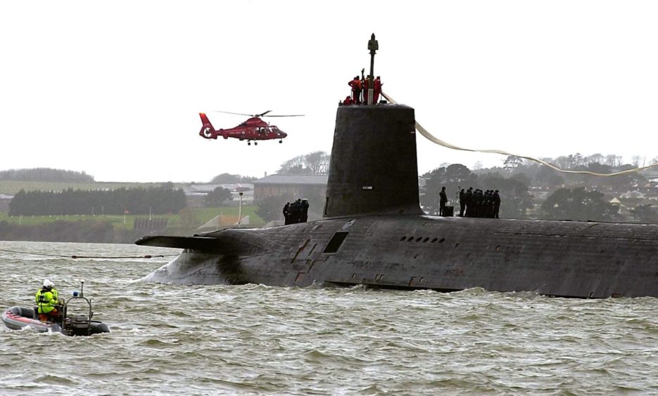 HMS Vanguard - a nuclear submarine in the sea with a helicopter flying overhead