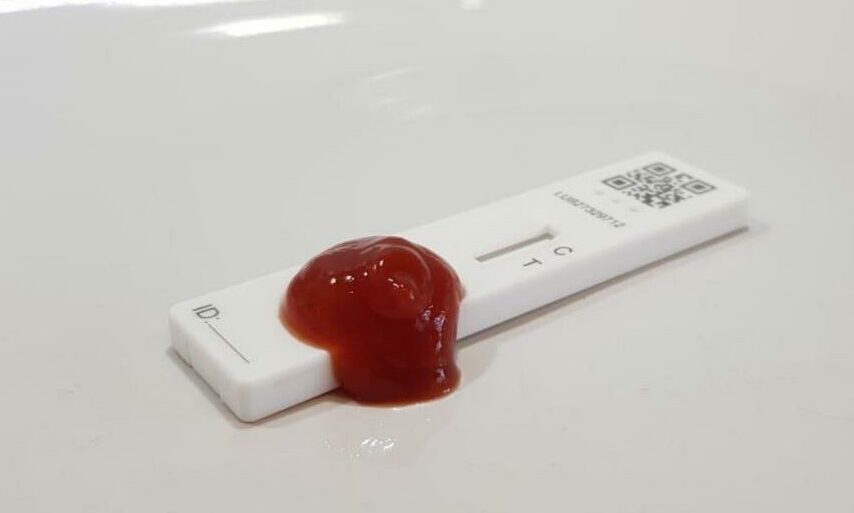 a rapid home covid test with tomato sauce on it