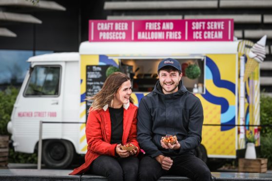 Chris Heather and Melodie Paterson smiling, sitting near the Heather Street Food van