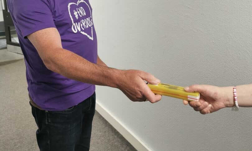 An ADA worker hands over a naloxone kit as part of their outreach work.