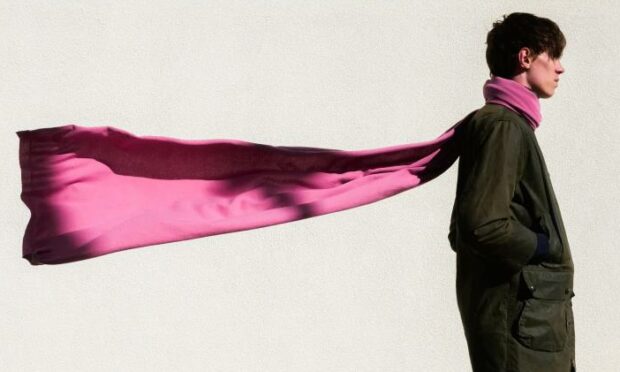 A large pink scarf from the Todd & Duncan Collection worn by a male model.