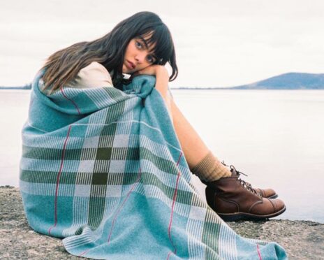 A blue tartan blanket from the Todd & Duncan Collection held by a female model.