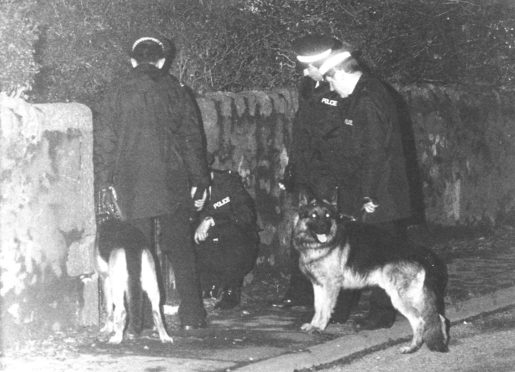 Police and police dogs examining an area of interest in Aberdeen after the George Murdoch murder