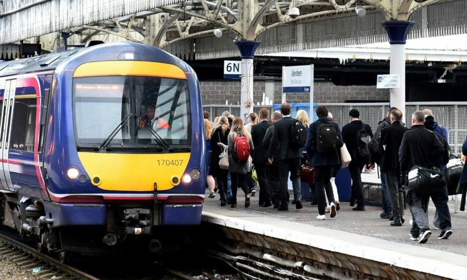 A ScotRail train at a platform with passengers walking past.