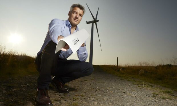 Edge Solutions managing director David Urch holding the armourEDGE in front of a wind turbine.