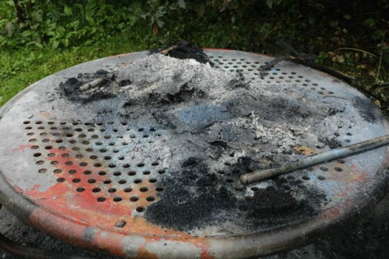 A fire-damaged picnic table at Clatto Park with the remains of a bin on top of it.