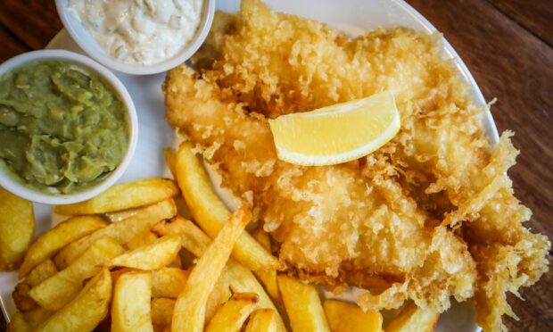 A plate of fish and chips with mushy peas and tartar sauce