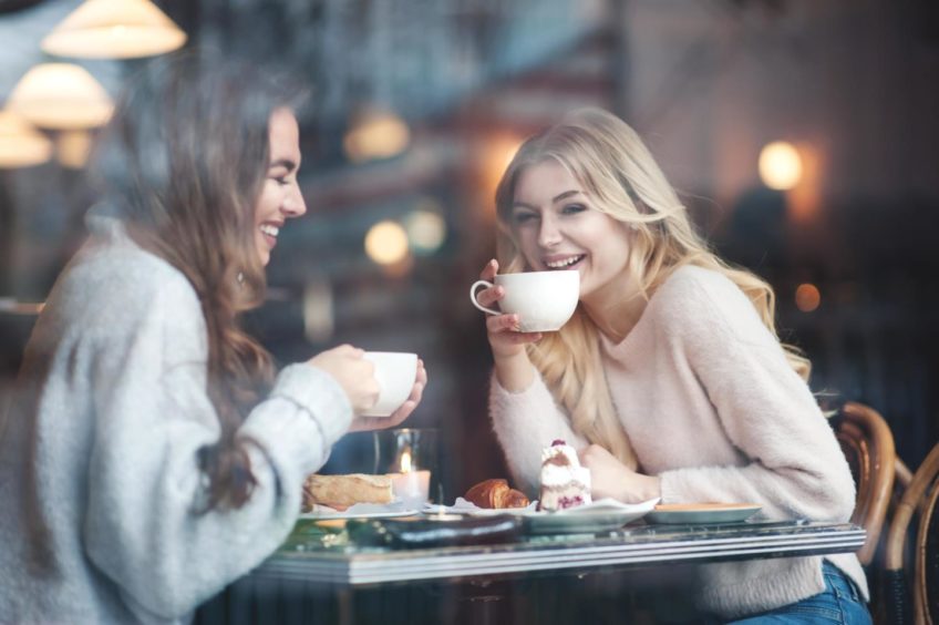 Two friends share a laugh in a cafe.