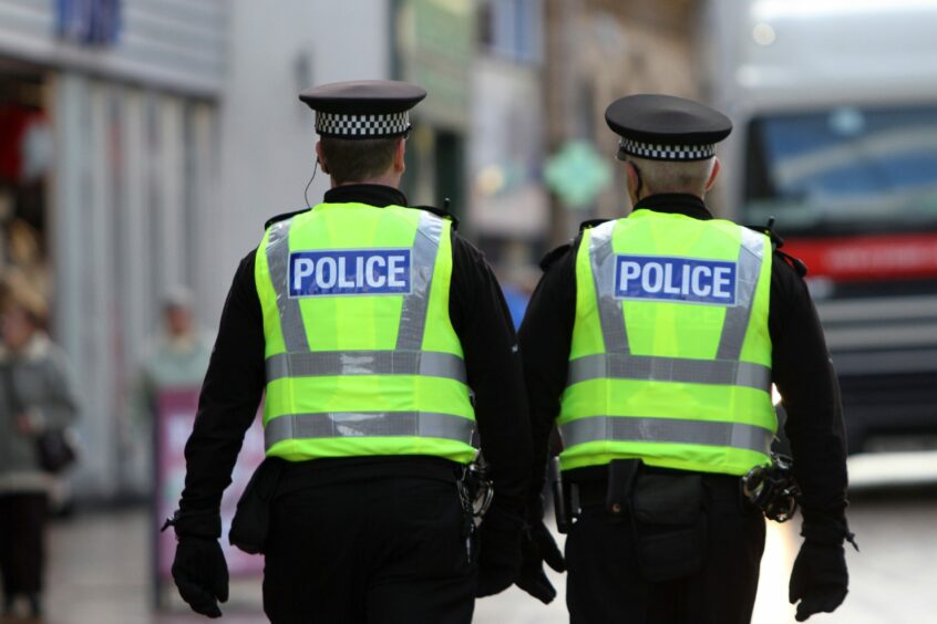 Rear view of two police officers on patrol on a shopping street.