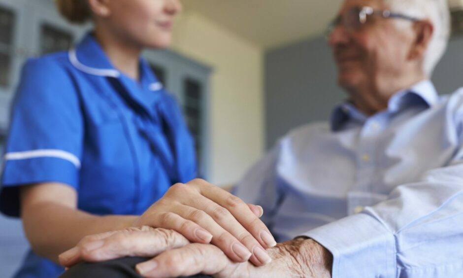 A nurse holds a pensioner's hand. 