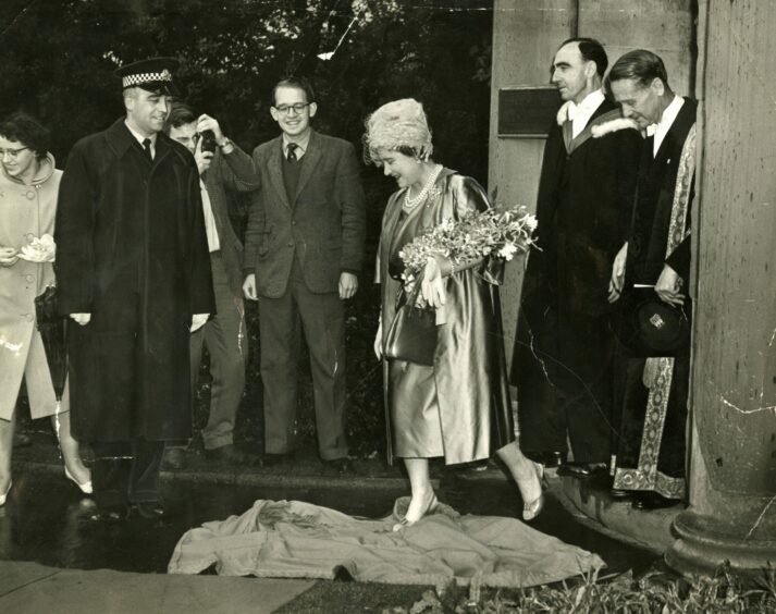 The Queen Mother stepping on a cloak during the Walter Raleigh moment at the unveiling ceremony.