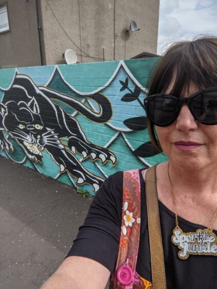 Vanessa Gibson in front of the mural of what the beast could look like.