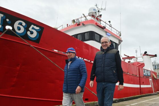 Two fisherman walking near a fishing boat in Peterhead, Scotland