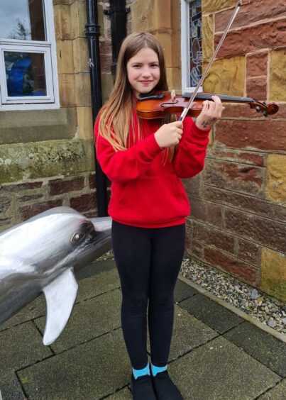 Joni Munro, a Cromarty Primary P6 and the 4,000th music pupil with High Life Highland, shows off her new violin.