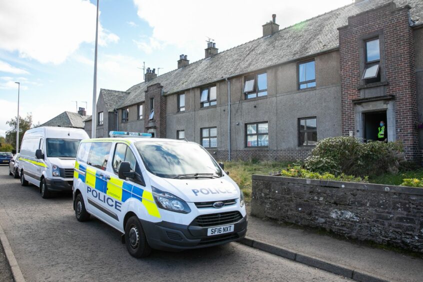 A police van and fire van parked outside a block of flats in Forfar following a fatal fire.