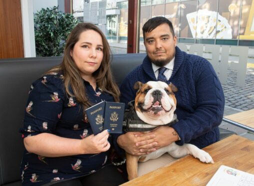 Student Jordan Brown with his fiancée Samantha Angulo and their dog Jimbo, sitting at a table showing their passports.