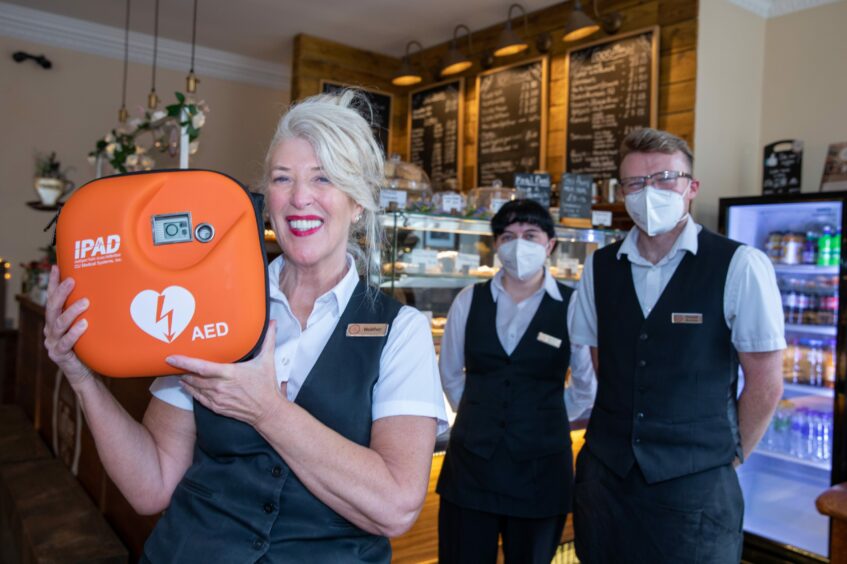 Staff at Coffee and Co in Dundee holding a defibrillator.