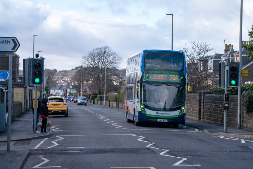 A double-decker Stagecoach bus driving past a pedestrian crossing on a road in Monifieth.