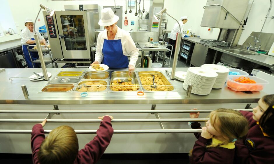 A dinner lady handing out free school meals in a canteen